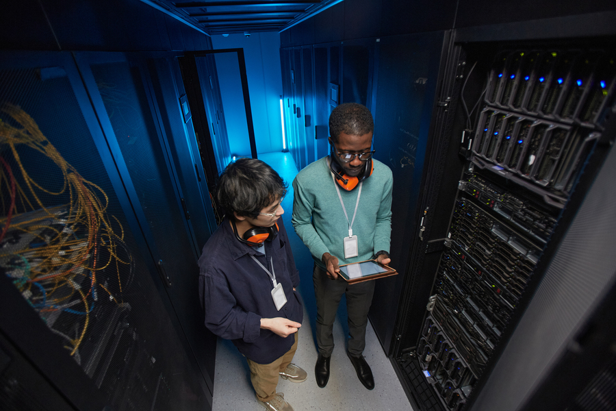 High angle view at two young technicians setting up server network while working in data center, copy space